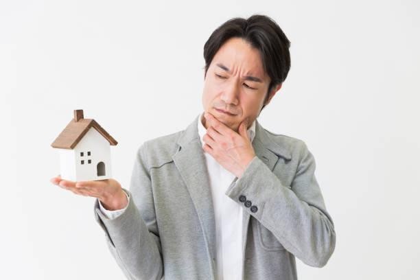Person considering a property decision while holding a small model house in St Kilda, Victoria